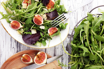 Autumn salad of arugula, figs in a white earthenware plate.