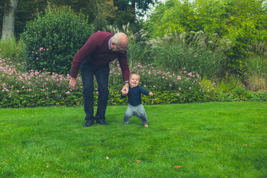 Grandfather running with grandson on lawn