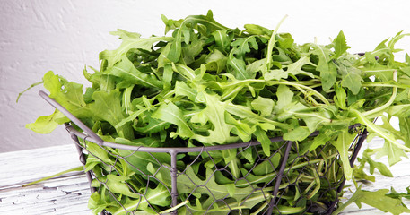 Fresh green arugula in basket on wooden table. Arugula is rich in vitamins and trace elements.