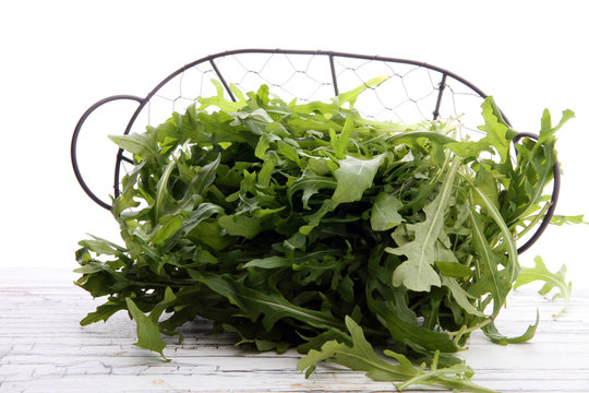 Fresh green arugula in basket on wooden table. Arugula is rich in vitamins and trace elements.