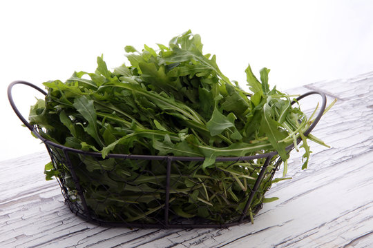 Fresh green arugula in basket on wooden table. Arugula is rich in vitamins and trace elements.