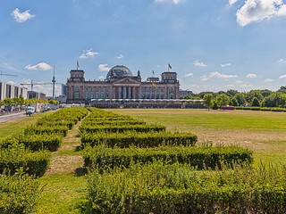 Reichstag in Berlin mit Park im Vodergrund aufgenommen im Sommer 2013 von der  Paul Löbe Allee mit blauem Himmel und Glaskuppel
