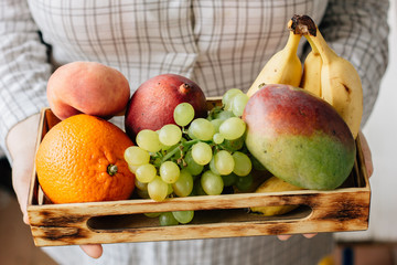 Woman holding box with fruits in hands.