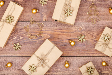 Fototapeta na wymiar homemade wrapped christmas and new year present boxes and decoration on wooden background. holiday and celebration concept. above view, flat lay.