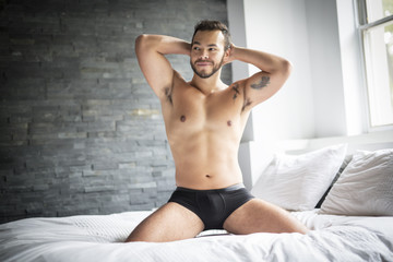 young man shirtless in white bed