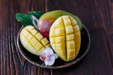 Fresh ripe mango with leaves and flower over wooden table