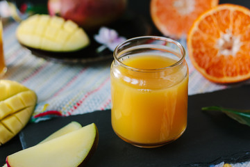 Mango and orange detox juice over black slate board.