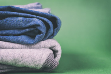 Warm and fashionable women's denim clothing folded on a colored background.