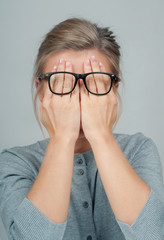 Tired woman in eyeglasses, covering face eyes hands