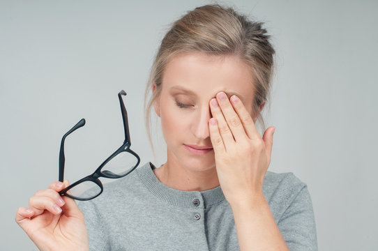 Tired woman with eyeglasses, covering eye with hands