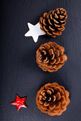 Background Christmas and New year Concept Pine cones and nuts with ceramic decoration  on black slate stone background