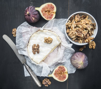 concept of appetizers for wine, camembert cheese, dark grapes, walnuts and figs with honey, on a wooden rustic background  space for text