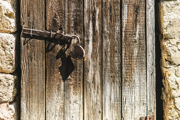Old wooden door in the village with a large rusty lock