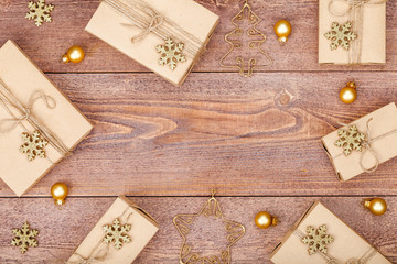 frame made of homemade wrapped christmas and new year present boxes and decoration on wooden background with copy space for text. holiday and celebration concept. above view, flat lay.