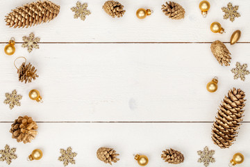 christmas or new year frame composition. christmas decorations in gold colors on wooden background with empty copy space for text. holiday and celebration concept for postcard or invitation. top view