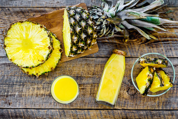 Freshly squeezed pineapple juice near fruit slices on wooden background top view