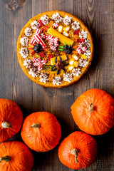 Homemade pie for halloween decorated gummy spiders among pumpkins on wooden background top view