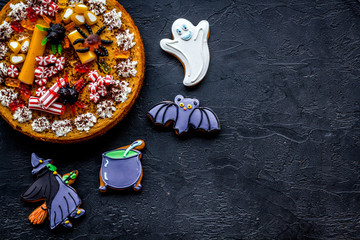Halloween bakery and sweets. Pumpkin pie, gummy spiders, gingerbread cookies on black background...