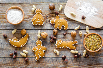 Healthy food for sportsman. Cookies in shape of yoga asanas near nuts on wooden background top view copyspace