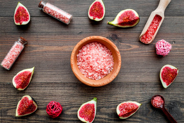 organic cosmetic set with fresh fig, bath salt and scrub on dark wooden background flat lay