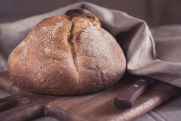 Homemade round bread on a wooden board, close-up