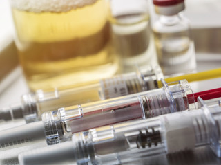 Several vials and syringe in laboratory, conceptual image