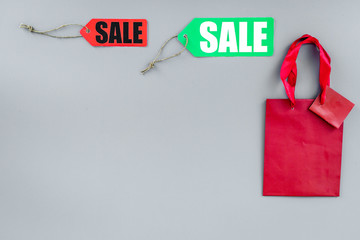 Sale label near paper shopping bag on grey background top view copyspace