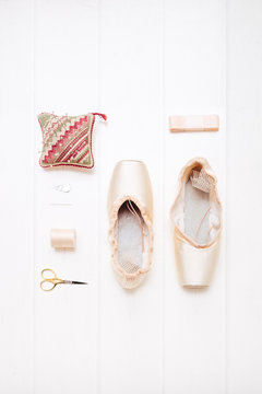 A new pair of pointe shoes set out with sewing kit and ribbons