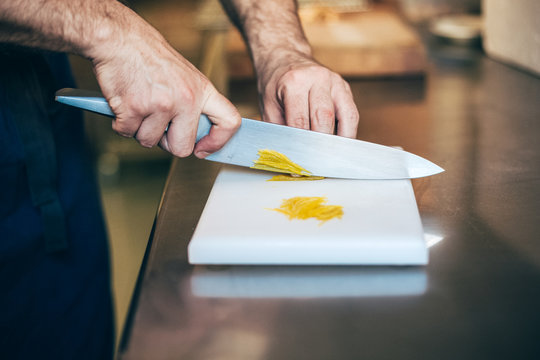 Men's hands cutting lemon zest on a cutting board