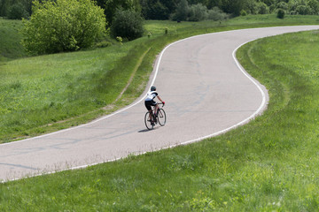 Obraz premium Sport. Cyclist riding a bike on an open road. Green field and trees as a background