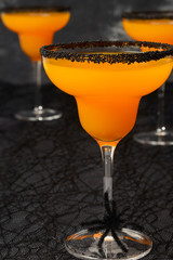 creepy Halloween cocktail, orange margarita with black sugar rim