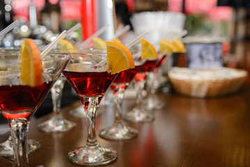 red cocktail with lemon and orange standing on a table in the bar