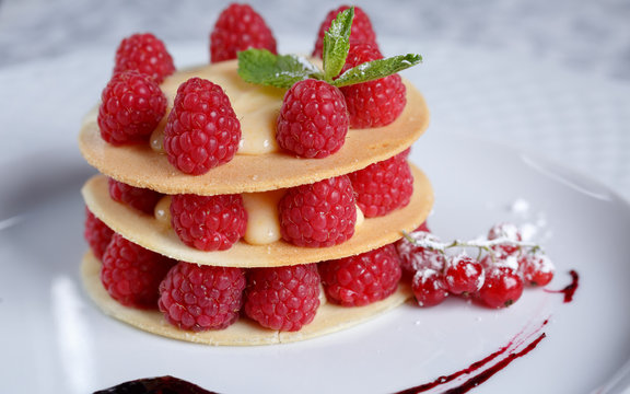Exquisite dessert with cookies, cream and raspberries