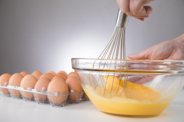 Hand rührt Eier für Rührei in Glas Schale mit Schneebesen