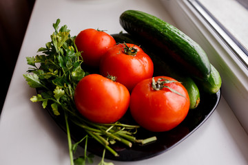 tomatoes, cucumbers and parsley on a black plate