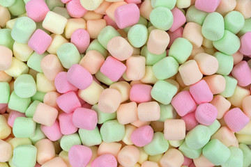 Close view of colorful pastel hued miniature green, pink, yellow and orange marshmallows.