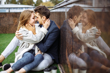 Young loving couple relaxing on grass and hugging, she is smiling and leaning on his shoulder, relationships and feelings concept.