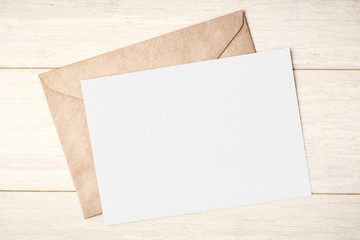 Blank white card and envelope on wooden table