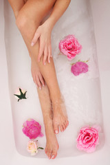 Obraz na płótnie Canvas Woman with beautiful legs taking a bath with flowers.