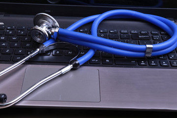 Blue medical stethoscope on a dark laptop computer