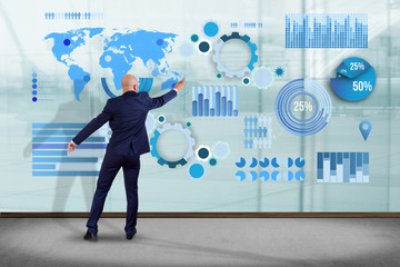 Businessman in front of a wall writing on a business graph and chart interface - business concept