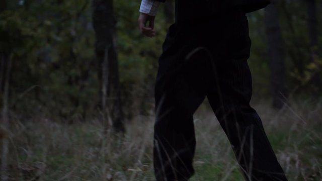 Mysterious headless figure in a business suit with a butterfly walking in the dark forest on the eve of halloween