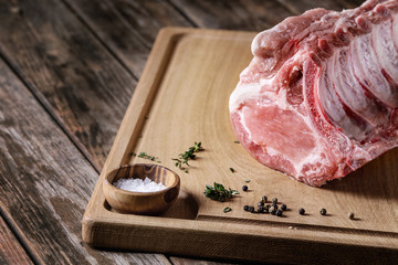 Fresh raw uncooked whole rack of pork loin with ribs on wooden cutting board with salt, thyme and...