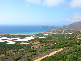 Panoramic view of Falasarna on Crete island, Greece. Lagoon of Falasarna beach with turquoise water and sandy beaches for rest. Plain is used for agriculture: greenhouses and gardens of olive trees. 