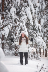 Happy woman on the winter background. Young pretty girl in the woods outdoors. Portrait of a cheerful beautiful woman.