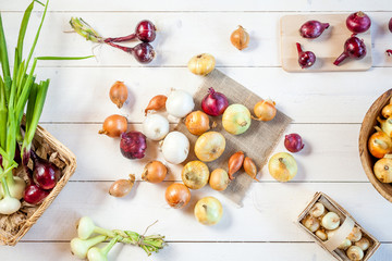 various fresh onions on a wooden table background. wallpaper for grocery shopping and cooking food concept. top view, flat lay