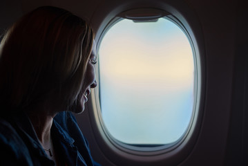 Young beautiful woman looking into the airplane window - 177821724