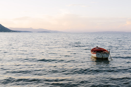Small rowing boat anchored just off shore on calm water at twilight