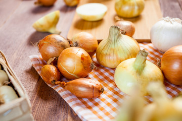 various fresh onions on a wooden table. wallpaper for grocery shopping and cooking food concept
