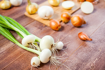 various fresh onions on a wooden table. wallpaper for grocery shopping and cooking food concept